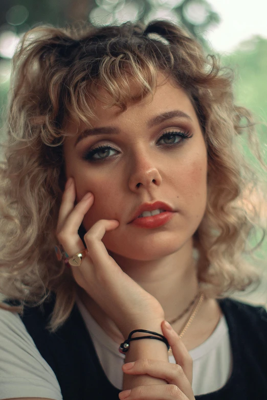 a woman sitting at a table with a cell phone to her ear, an album cover, inspired by Nan Goldin, trending on pexels, photorealism, chloe grace moretz, curly bangs, eighties-pinup style, serious face