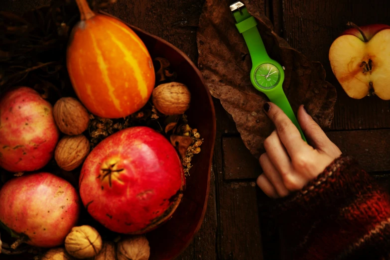 a person holding a green watch over a bowl of fruit, during autumn, premium, profile image, festive