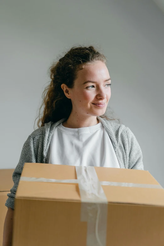 a woman holding a box in her hands, pexels contest winner, slightly smiling, avatar image, caucasian, ecommerce photograph