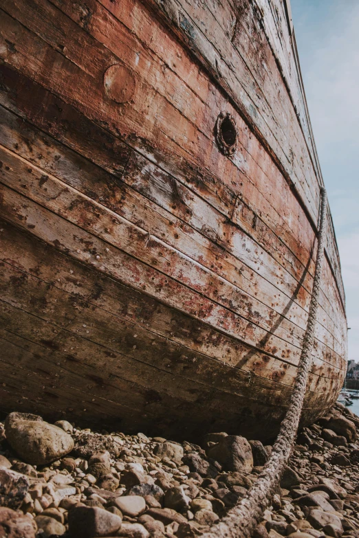 a boat sitting on top of a rocky beach, cracked varnish, weathered skin, top selection on unsplash, heavy detailed