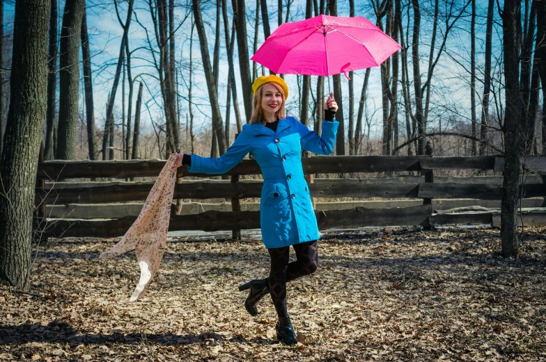 a woman in a blue coat holding a pink umbrella, photo taken with provia, yellow raincoat, fun pose, enjoying a stroll in the forest