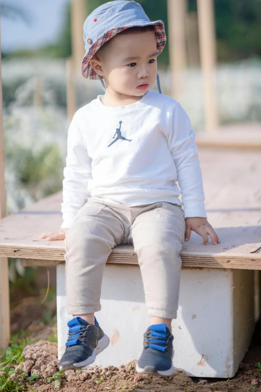 a little boy sitting on top of a wooden bench, inspired by Kinichiro Ishikawa, unsplash, “air jordan 1, long sleeves, khakis, white