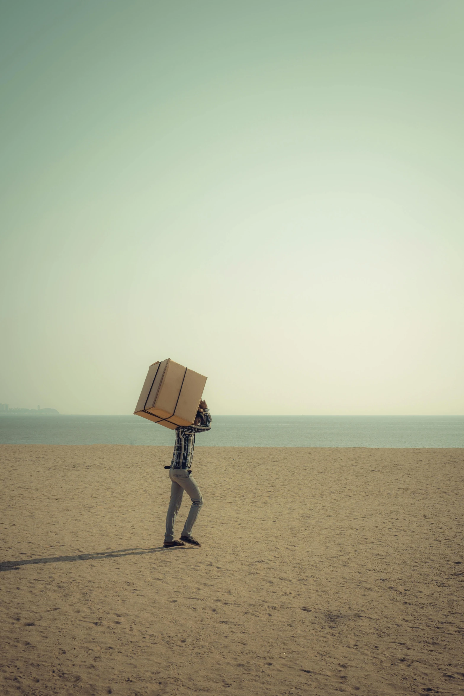 a man walking on a beach with a box on his head, unsplash, conceptual art, square, luggage, panels, shady