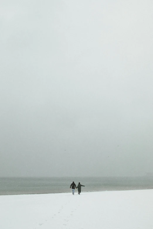 a couple of people standing on top of a snow covered beach, unsplash, minimalism, foggy heavy rain, surfing, 33mm photo, made of mist