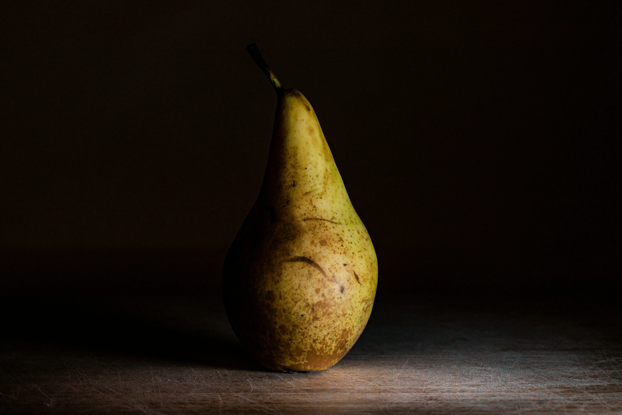 a pear sitting on top of a wooden table, a still life, unsplash, photorealism, under a spotlight, brown, full frame image, evenly lit