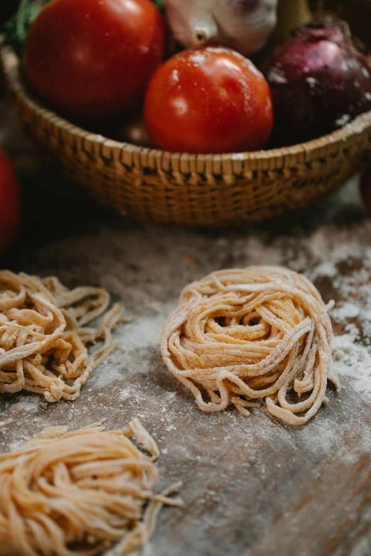 a bowl of pasta sitting on top of a wooden table, fruit, thick dust and red tones, loaves, strings