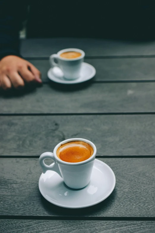 two cups of coffee sitting on top of a wooden table, by Carlo Martini, unsplash, square, sao paulo, man, small in size