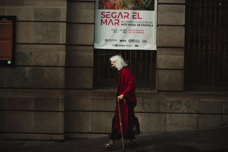 a woman in a red coat walking down a street, a poster, by Santiago Martínez Delgado, pexels contest winner, wise old man, banners, cinema poster, very long silver hair