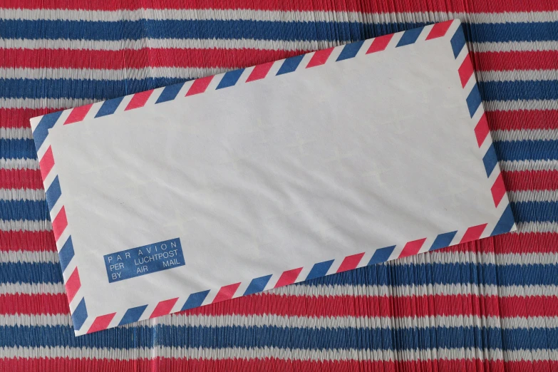 a close up of an envelope on a table, an album cover, by Romain brook, mail art, red and blue, vintage pilot clothing, striped, white