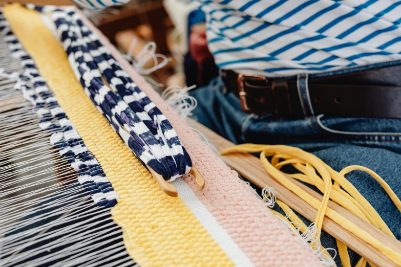 a close up of a person using a weaving machine, trending on pexels, arts and crafts movement, yellow and blue ribbons, al fresco, flatlay, sailor clothing