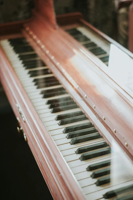 a close up of a piano keyboard on a table, an album cover, by David Simpson, unsplash, baroque, faded pink, vehicle, brown, long