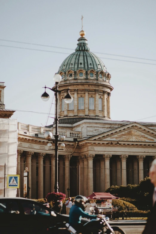 a man riding a motorcycle down a street next to a tall building, by Serhii Vasylkivsky, pexels contest winner, neoclassicism, neoclassical tower with dome, saint petersburg, brown, 000 — википедия