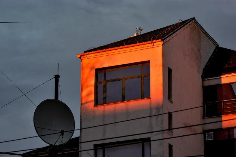 a building with a satellite on top of it, an album cover, inspired by Elsa Bleda, pexels contest winner, orange lamp, backlight, urban house, photograph taken in 2 0 2 0