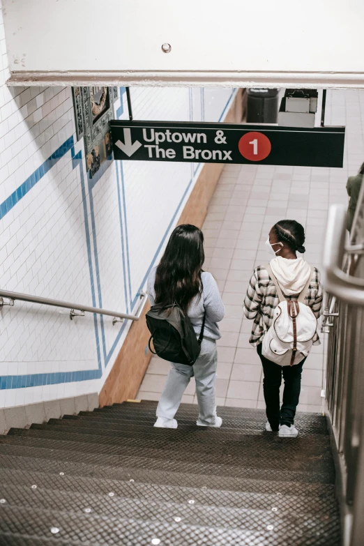 a couple of people that are walking up some stairs, by Carey Morris, trending on unsplash, mta subway entrance, young girls, brown, 🚿🗝📝