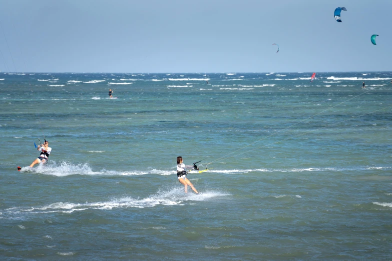 a couple of people riding water skis on top of a body of water, offshore winds, near the beach, seaview