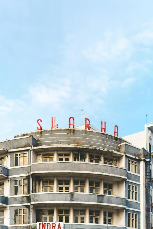 a large building with a sign on top of it, inspired by Bhupen Khakhar, trending on unsplash, brutalism, sahara comics logo, shanghai, wide high angle view, ( ( theatrical ) )