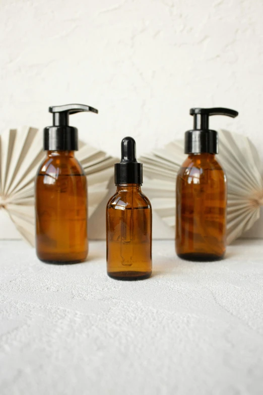 a couple of brown bottles sitting on top of a table, a picture, skincare, scientific glassware, thumbnail, oiled