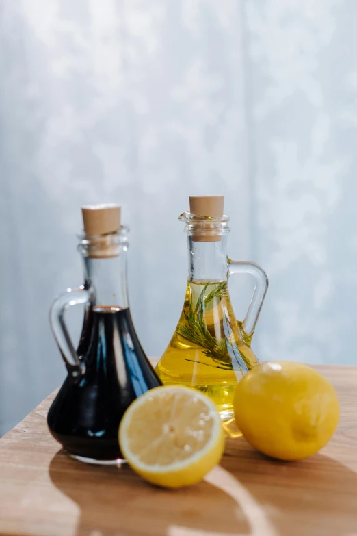 two bottles of olive oil and two lemons on a cutting board, inspired by Li Di, unsplash, renaissance, beautiful black blue yellow, square, black in, made of glazed