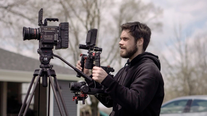 a man standing next to a camera on a tripod, graded with davinci resolve, zach hill, fujifilm”, hyperrealistic movie filmstill