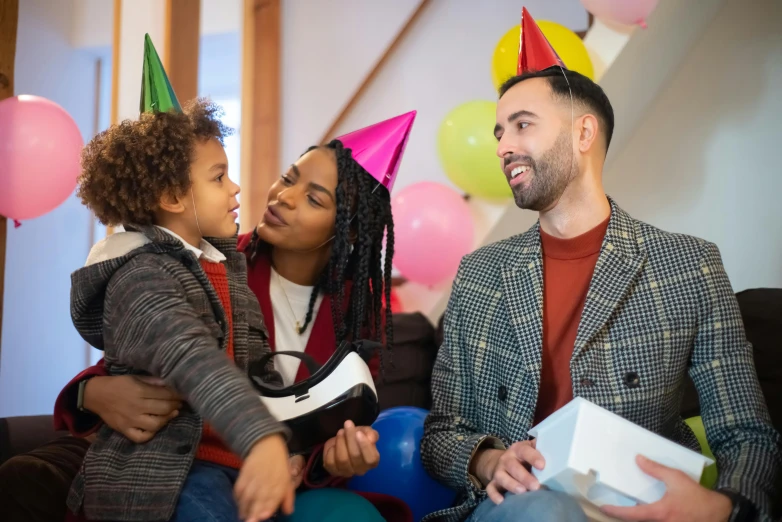 a man and woman sitting on a couch with a child, party hats, giving gifts to people, lgbtq, raphael lecoste