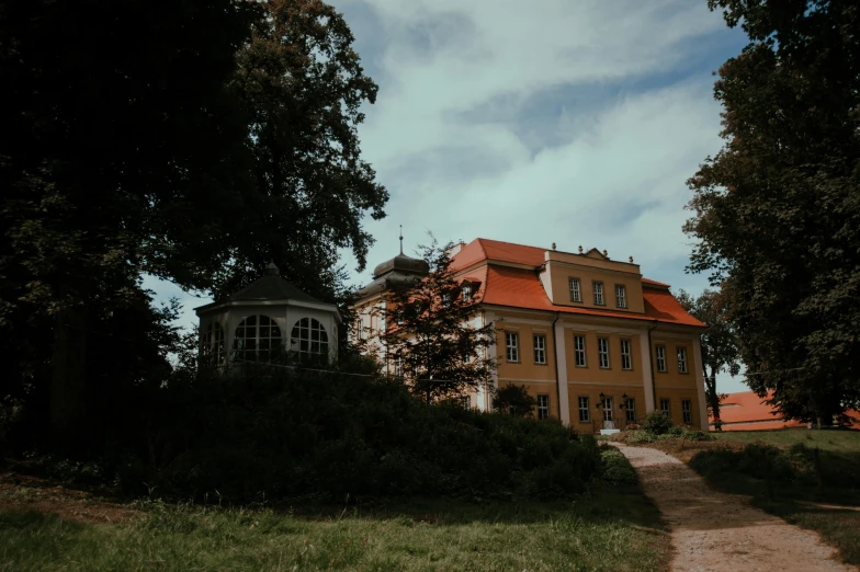 a large yellow house sitting on top of a lush green field, by Emma Andijewska, pexels contest winner, rococo, zdzislaw, front side, album photo, 2 0 0 0's photo
