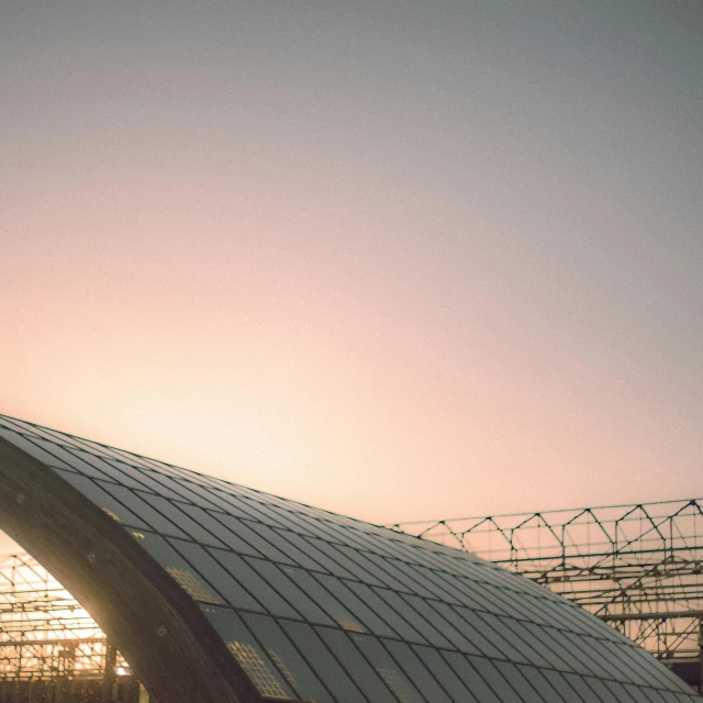 a man riding a skateboard up the side of a ramp, by Jakob Gauermann, pexels contest winner, modernism, sunrise over solarpunk city, rounded roof, train station, pink arches