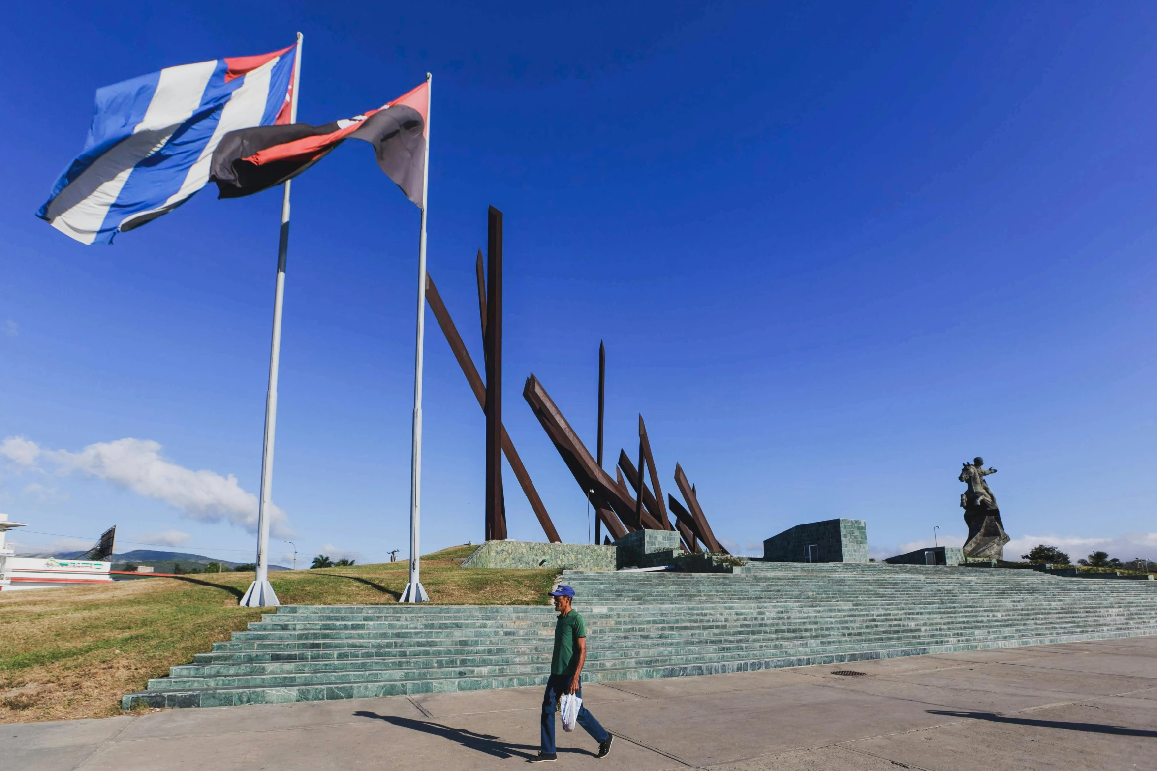 a person walking in front of a bunch of flags, by Juan Giménez, visual art, monumental structures, rust, puerto rico, square