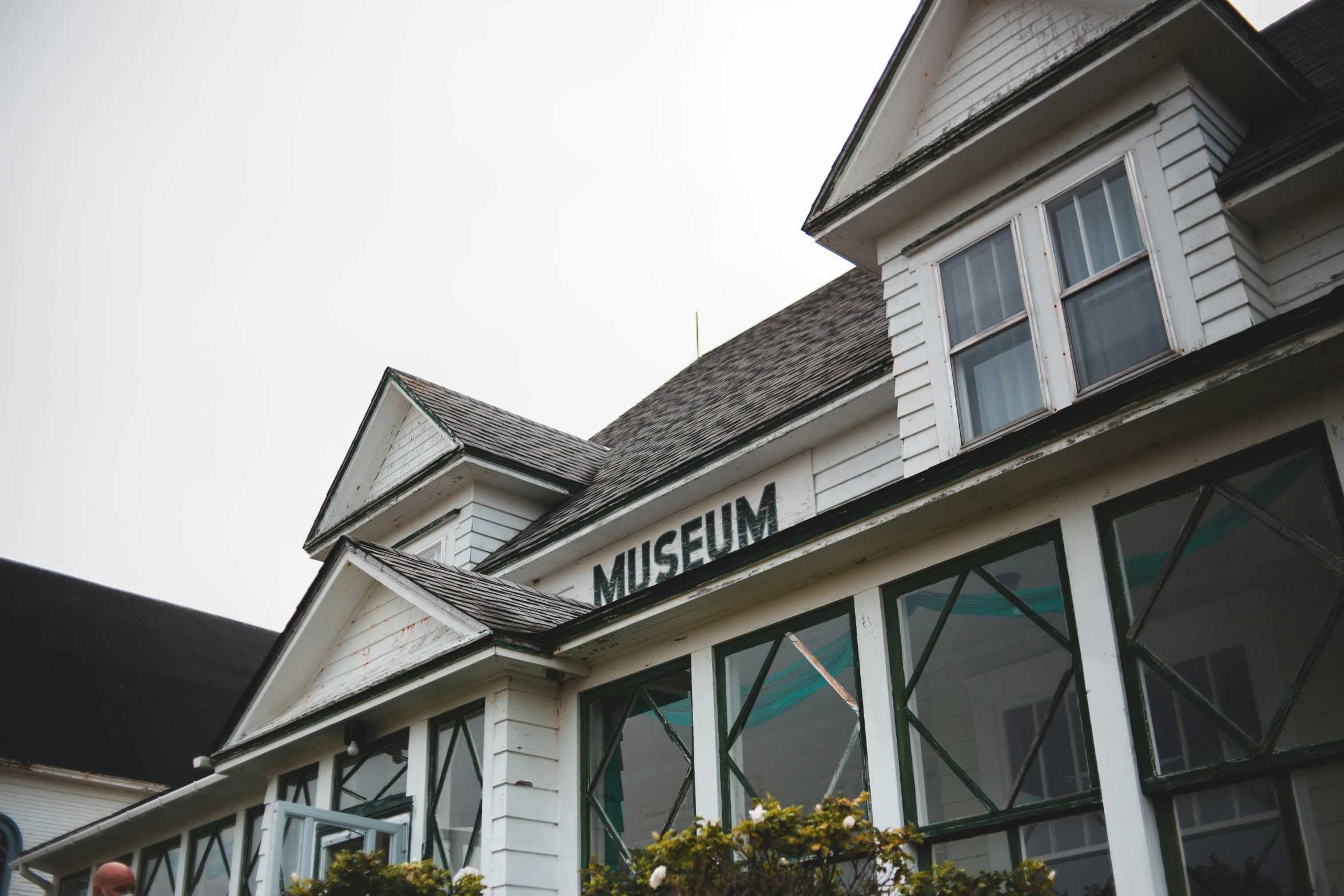 a white building with a sign on the front of it, an album cover, unsplash, arts and crafts movement, preserved museum piece, profile image, high - angle view, pavilion