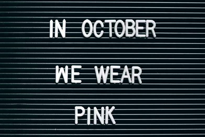 a sign that says in october we wear pink, a photo, trending on pexels, vantablack wall, cyber wear, punk, wolff olins