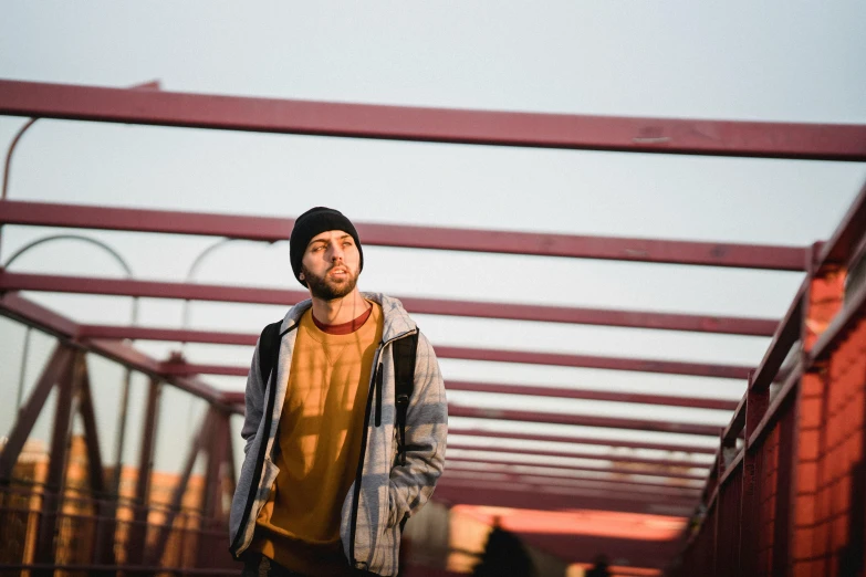 a man standing on a bridge holding a skateboard, a portrait, pexels contest winner, hat and hoodie, avatar image, pondering, anna nikonova