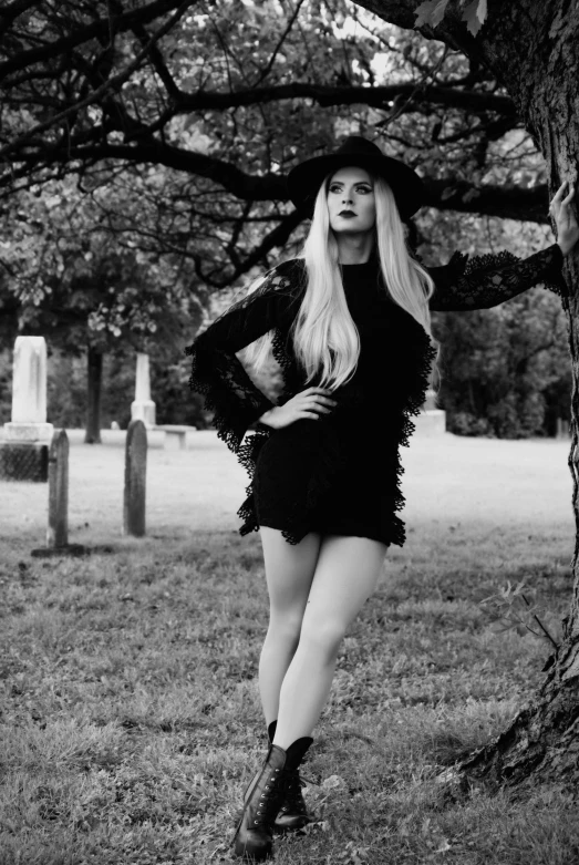 a woman standing next to a tree in a cemetery, inspired by Kati Horna, tumblr, portrait of kim petras, wearing black witch hat, monochrome!!!!!, katherine mcnamara inspired