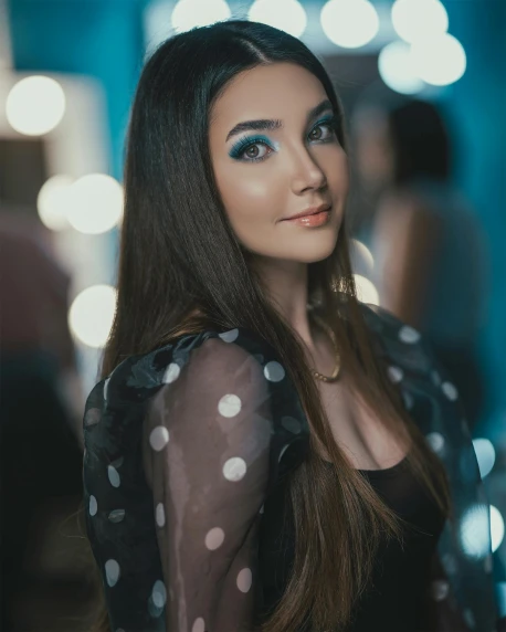a woman in a polka dot dress posing for a picture, inspired by Elsa Bleda, trending on pexels, teal lights, with professional makeup, beautiful iranian woman, looking straight to camera