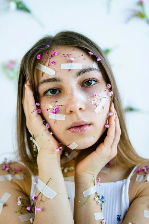 a woman with a lot of confetti on her face, an album cover, inspired by Elsa Bleda, trending on pexels, covered in bandages, pressed flowers, lovingly looking at camera, teenager