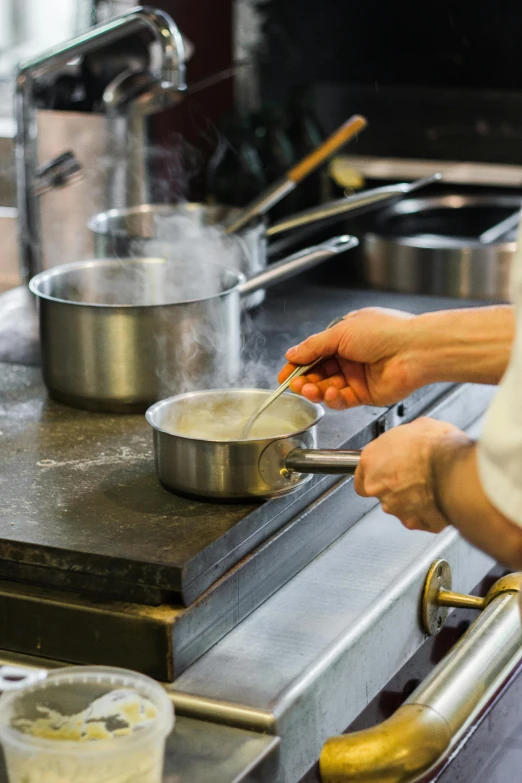 a person cooking food on a stove in a kitchen, michelin starred restaurant, thumbnail, metal kitchen utensils, kitchen counter