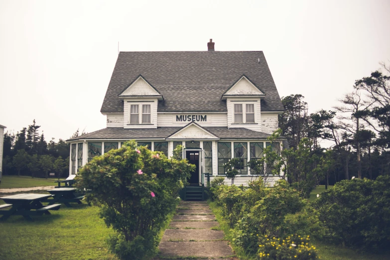 a large white house sitting on top of a lush green field, an album cover, unsplash, museum photograph, cottages, overcast day, exterior photo