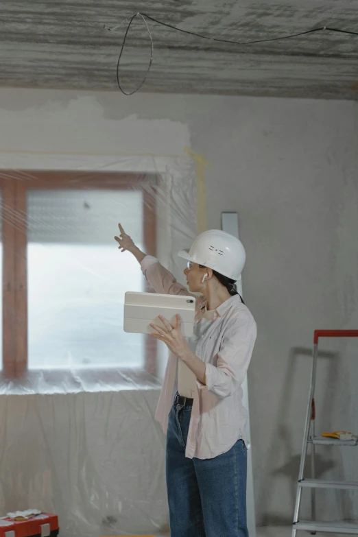 a woman standing in a room under construction, a hyperrealistic painting, pexels contest winner, home video footage, using a magical tablet, flour dust spray, pointing
