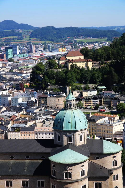 a large building sitting on top of a lush green hillside, viennese actionism, black domes and spires, aerial view of a city, brown, mount