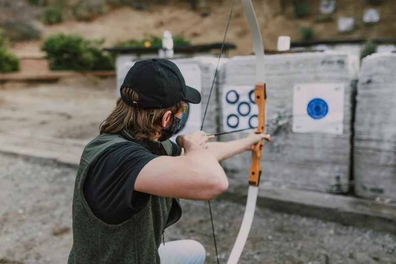 a man aiming a bow at a target, pexels contest winner, lachlan bailey, corinne day, casual game, holding a shield