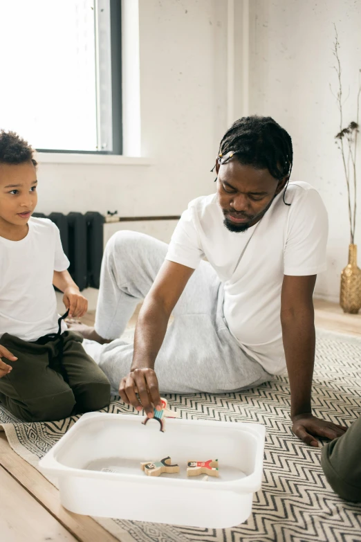 a man and a little boy sitting on the floor, a child's drawing, pexels contest winner, black arts movement, painting a canvas, gif, husband wife and son, paint pour