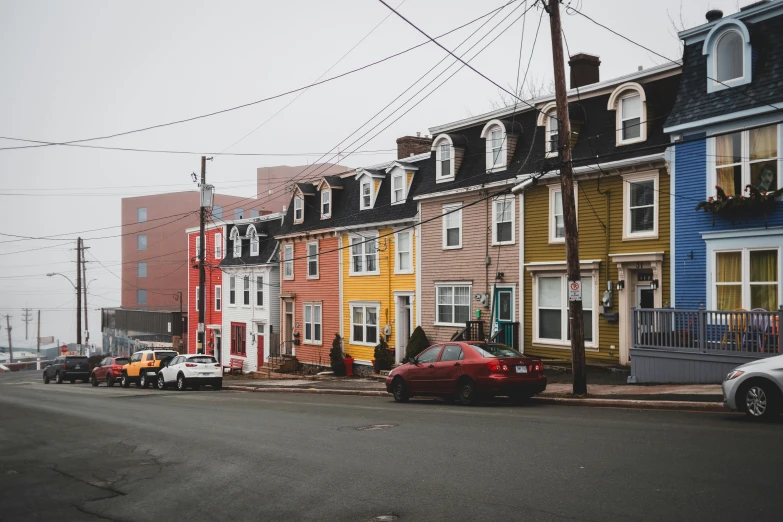 a group of cars parked on the side of a road, by Carey Morris, pexels contest winner, colorful houses, montreal, payne's grey and venetian red, colonial
