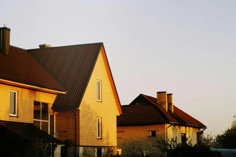 a couple of houses sitting next to each other, by Attila Meszlenyi, pexels contest winner, modernism, soft golden hour lighting, simple gable roofs, medium format. soft light, view from side