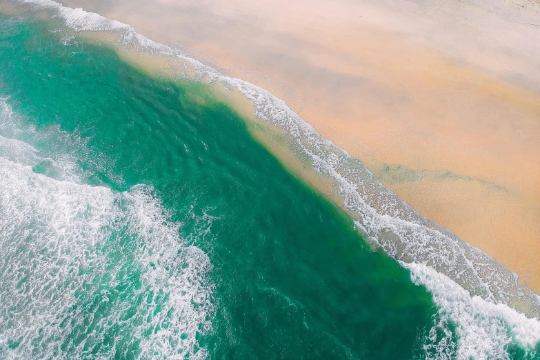 a large body of water next to a sandy beach, pexels contest winner, hurufiyya, seafoam green, aerial footage, ocean spray, a colorful