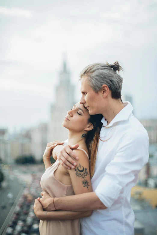 a man and a woman standing next to each other, a tattoo, pexels contest winner, romanticism, in moscow centre, city backdrop, embracing, pale grey skin