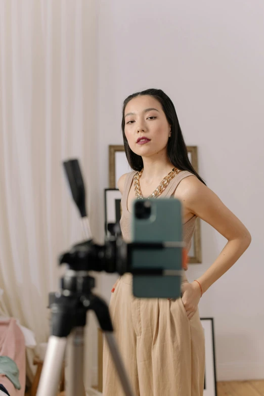 a woman standing next to a camera on a tripod, inspired by helen huang, trending on pexels, video art, wearing an elegant outfit, center frame portrait, live broadcast, li bingbing