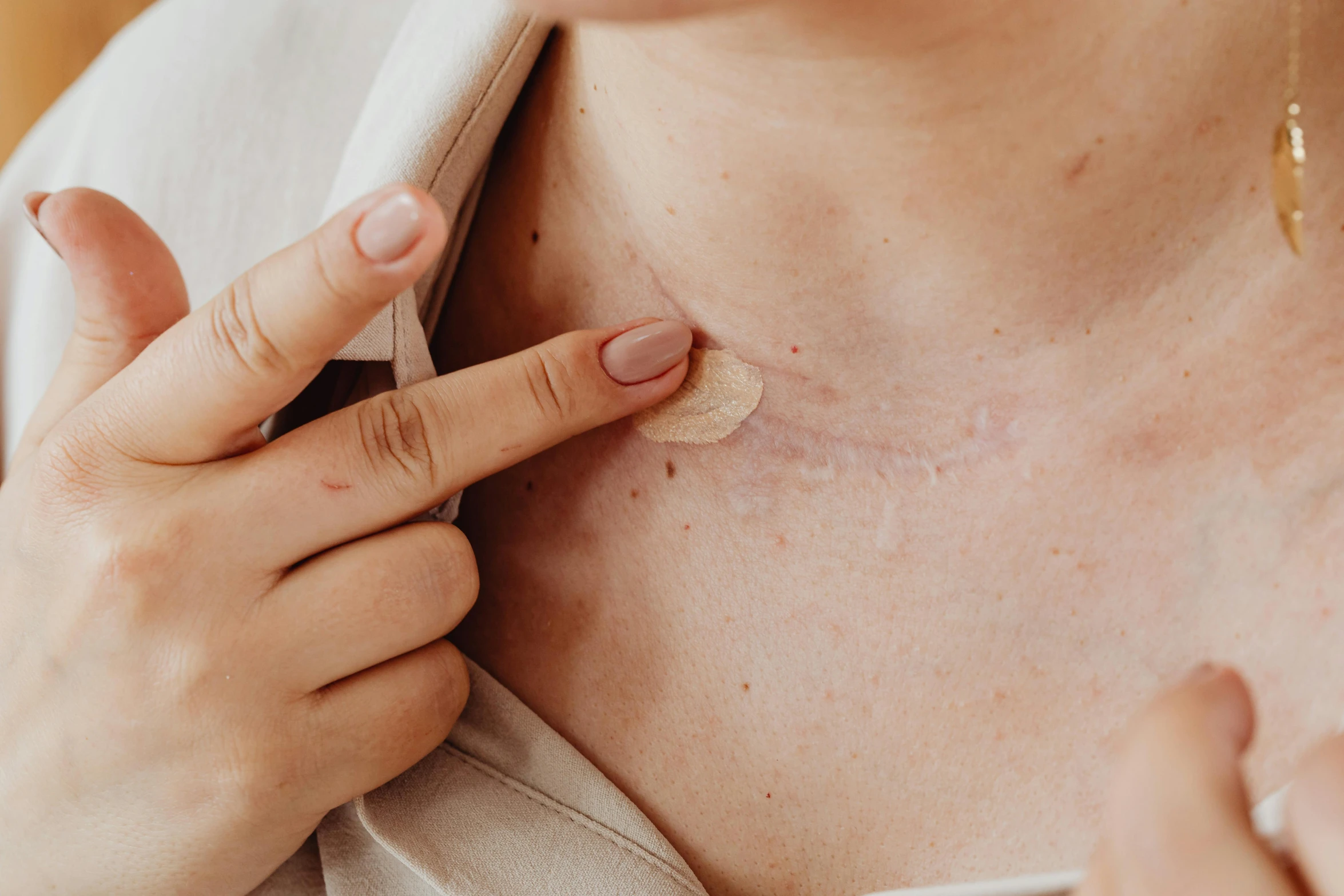 a woman putting a patch on her chest, trending on pexels, facial scar, necklace, manuka, full body image