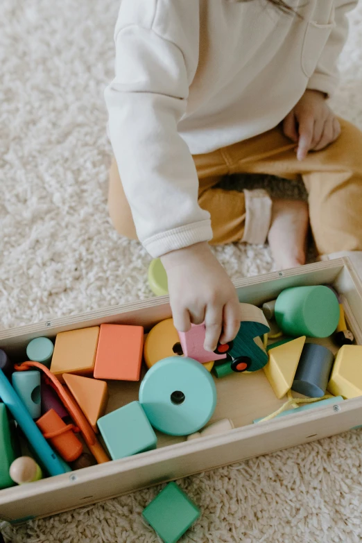 a toddler playing with wooden toys on the floor, pexels contest winner, muted pastels, blocky shape, promo image, brilliantly colored