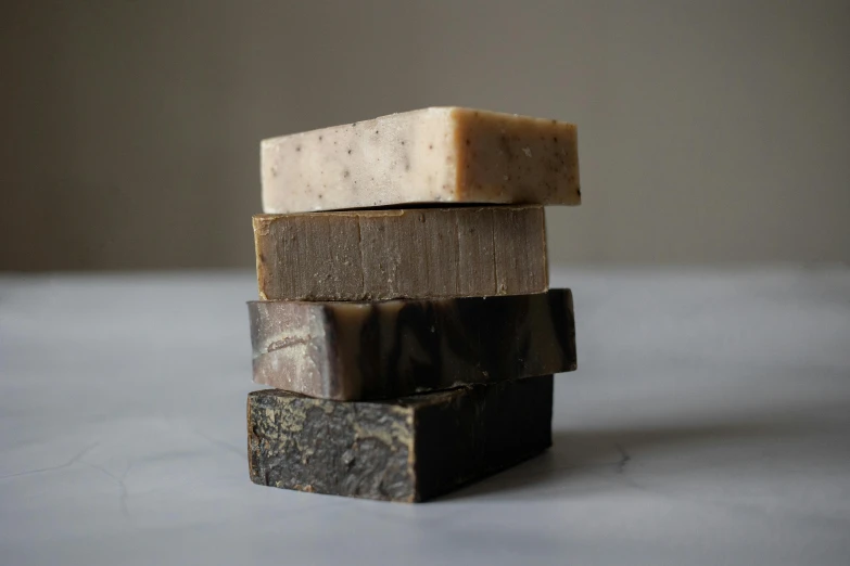 a stack of soap bars sitting on top of each other, by Jessie Algie, tiny charcoal smudges, diverse textures, oud, milk