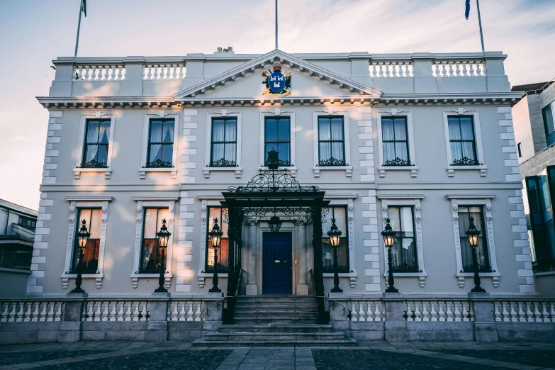 a large white building with a flag on top of it, inspired by Prince Hoare, unsplash, richly decorated victorian house, blue hour lighting, entrance, hull