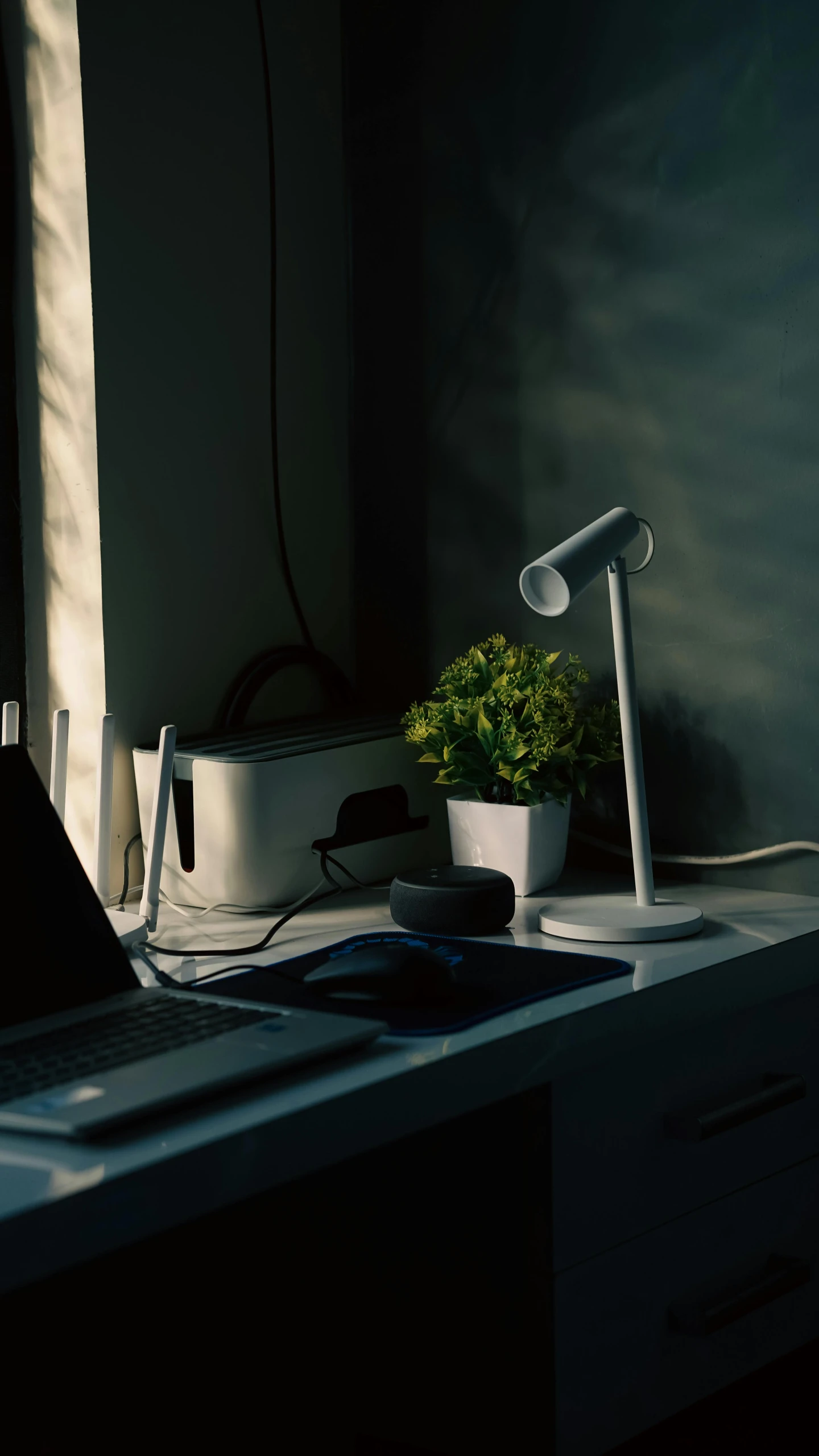 a laptop computer sitting on top of a white desk, bloom lighting, eora, table with microphones, dimly lit interior room