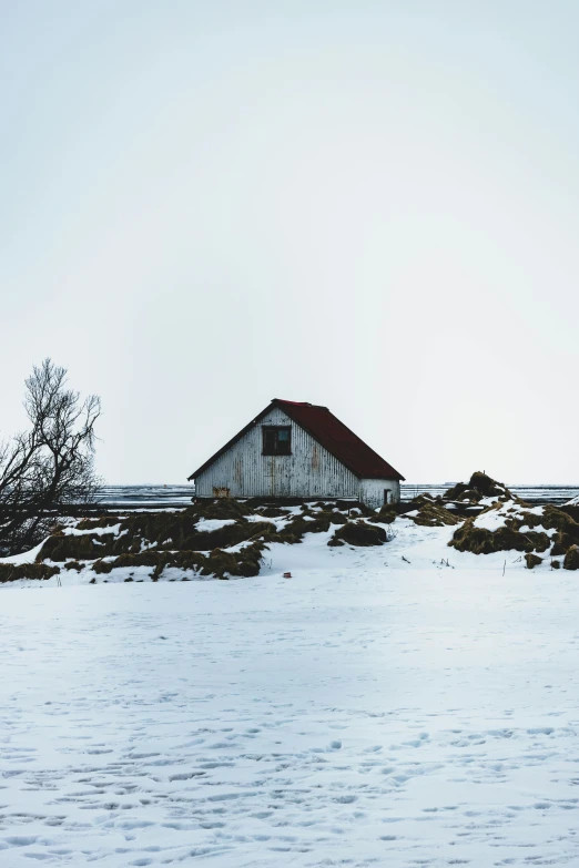 a barn sitting on top of a snow covered hill, by Hallsteinn Sigurðsson, pexels contest winner, minimalism, plain background, vintage color photo, looking to the side, background image